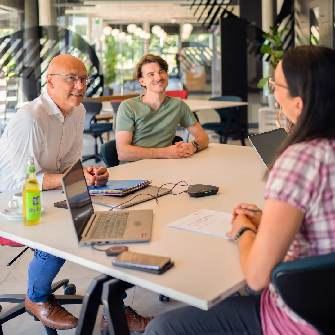 Teambesprechung im Innovation Hub Halle (Saale) - drei Personen sitzen an einem Tisch mit Laptops